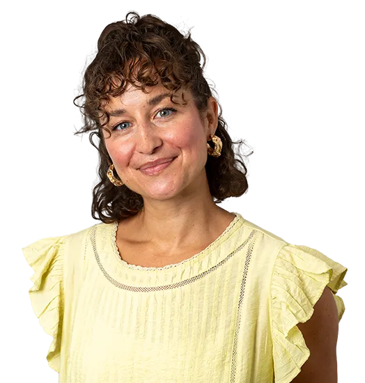 Smiling woman with curly hair and bangs wearing a pastel yellow blouse.