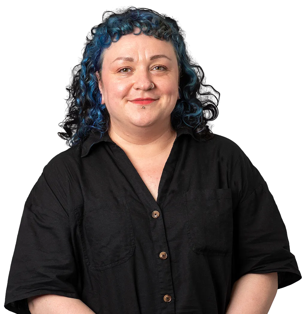 Smiling person with curly blue hair wearing a black button-up shirt on a black background.