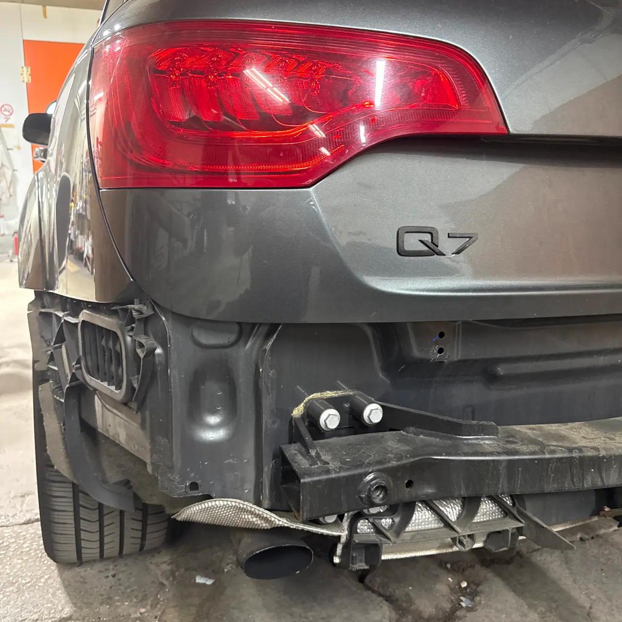 A gray SUV with its rear bumper removed.