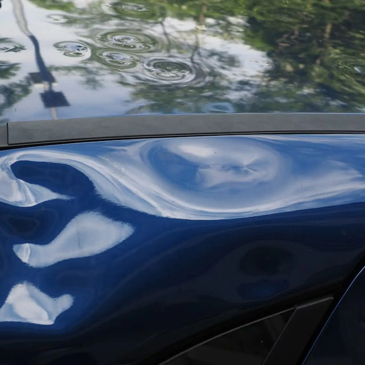 Closeup of a dented blue car.