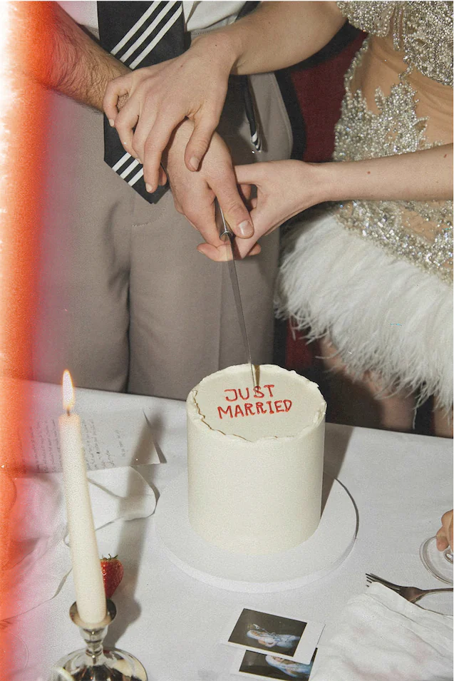 Photo of couple cutting into a cake that says "Just Married"
