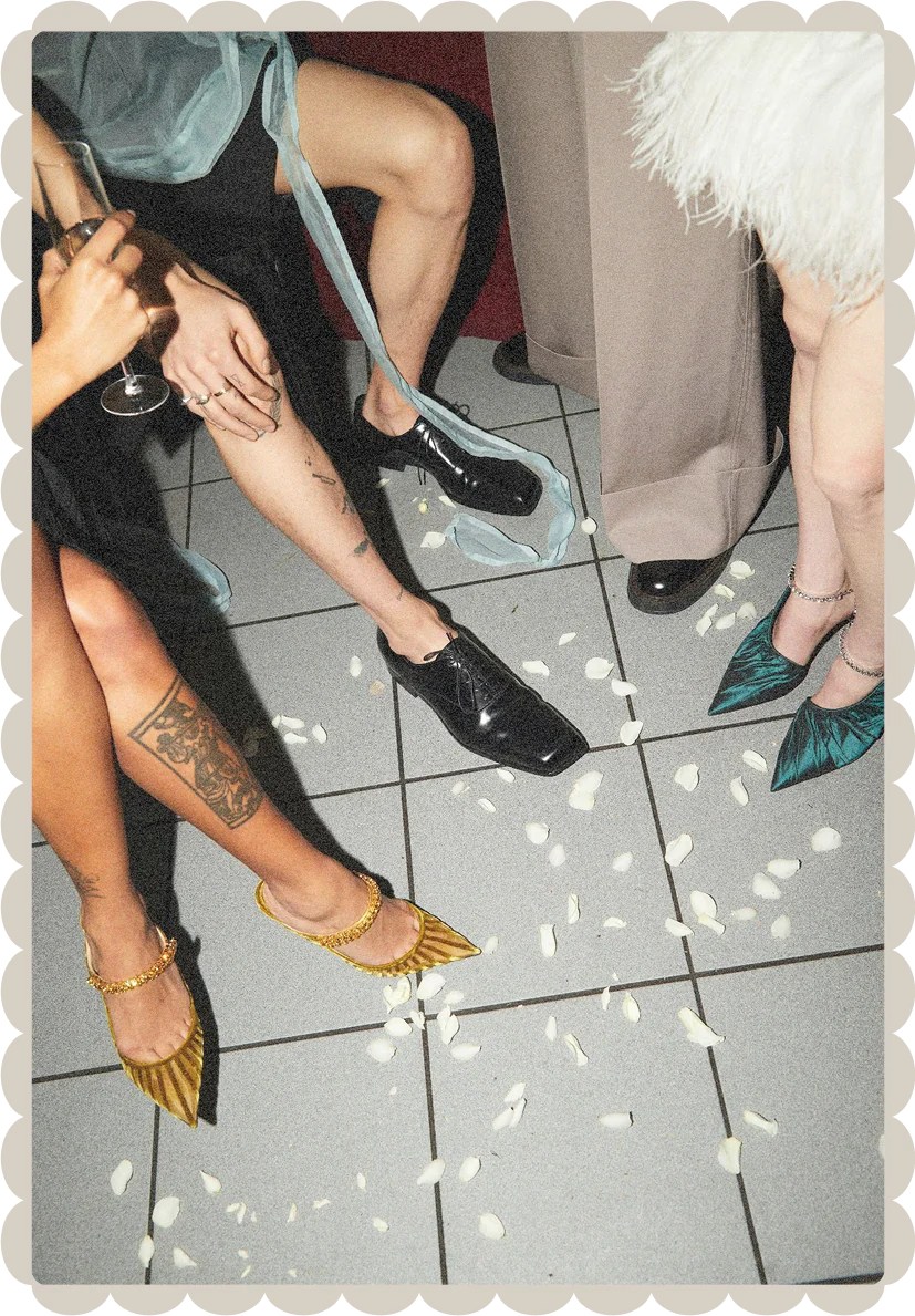 Photo of partygoers feet with heels, champagne, and flower petals.