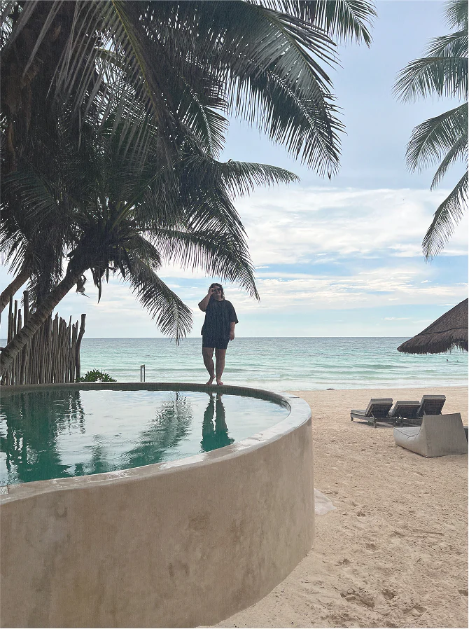 Gabi, one of our founders, standing on the edge of a pool in Tulum.