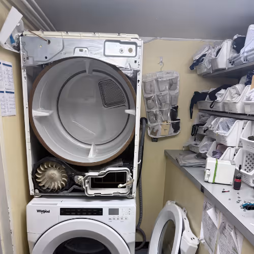 Open dryer revealing internal components in a laundry storage room