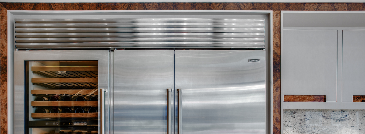 Stainless steel Sub-Zero refrigerator with double doors and an integrated wine cooler on the left side.