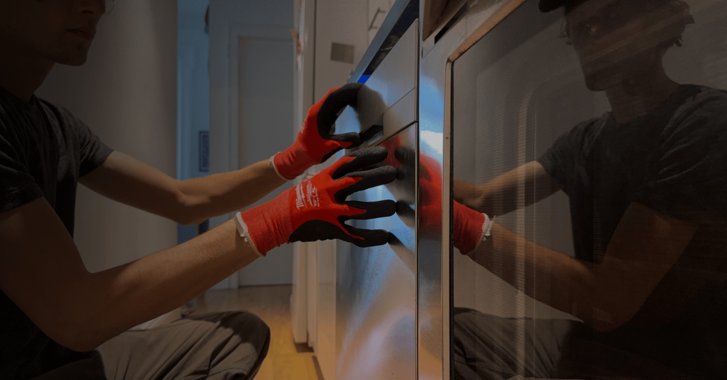 Hands in red and black work gloves installing glass panel