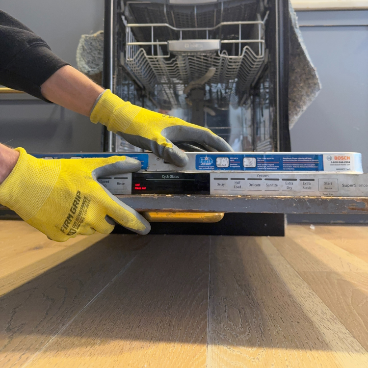 Person wearing yellow gloves opening a Bosch dishwasher door with cycle status and control buttons visible.