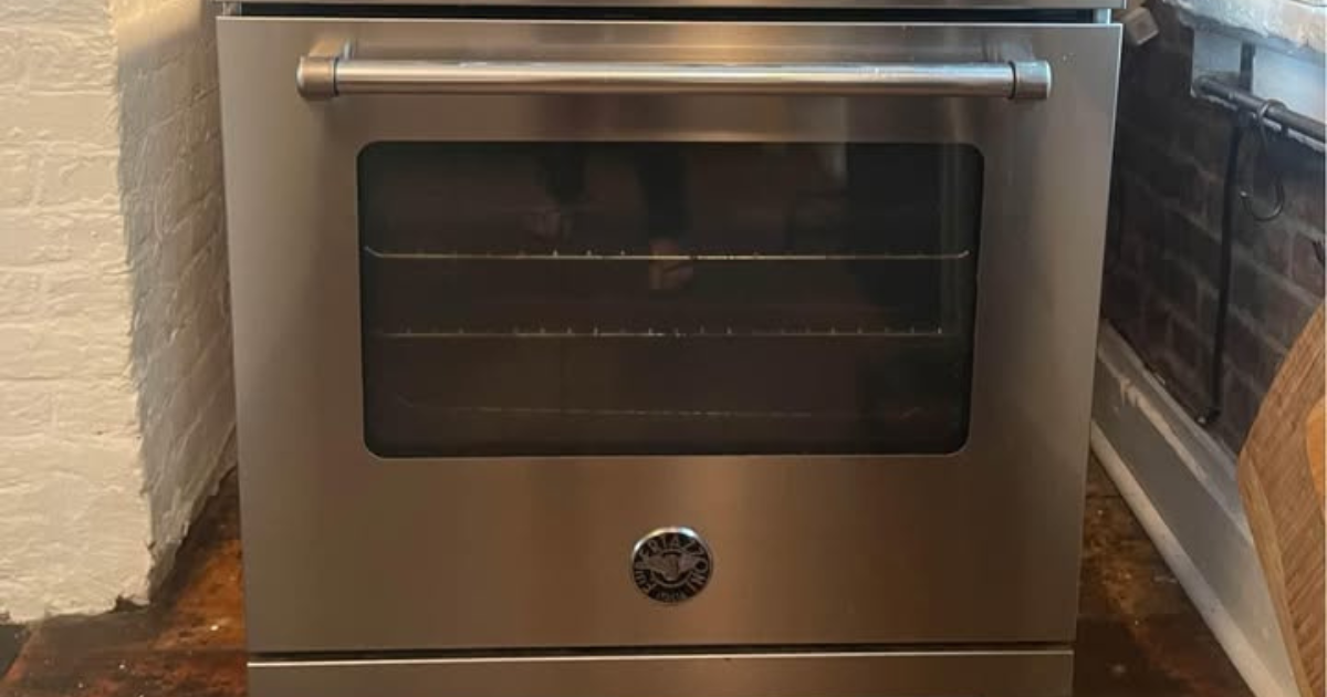 Three cats lying closely together on a white towel indoors, appearing relaxed and sleepy.