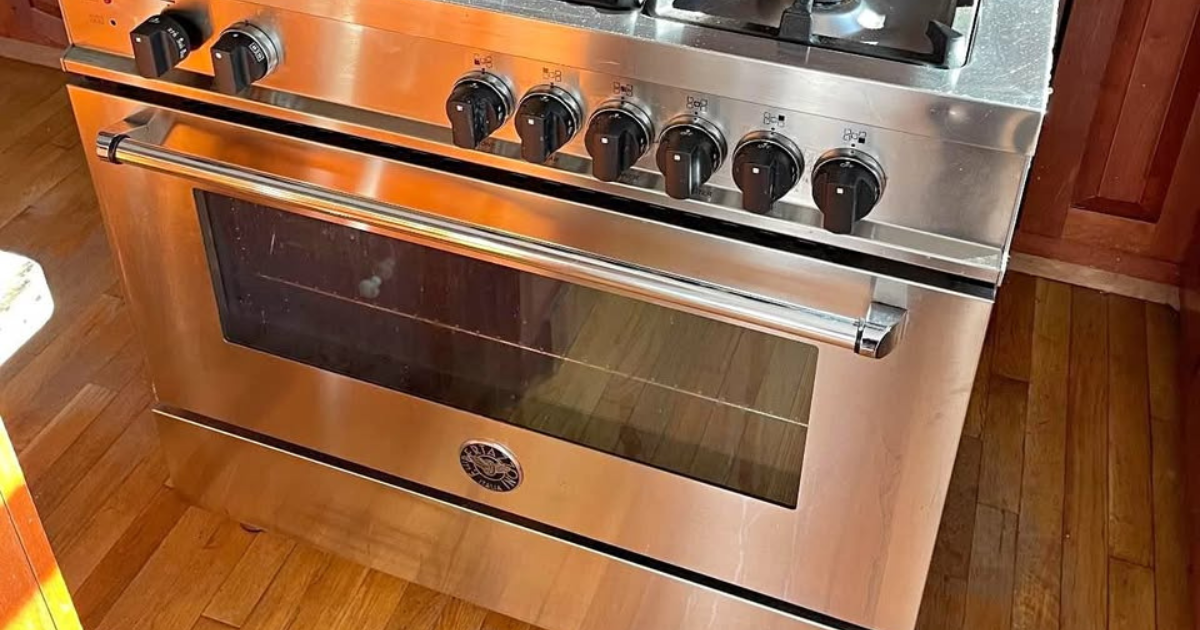 Three cats lying closely together on a white towel indoors, appearing relaxed and sleepy.