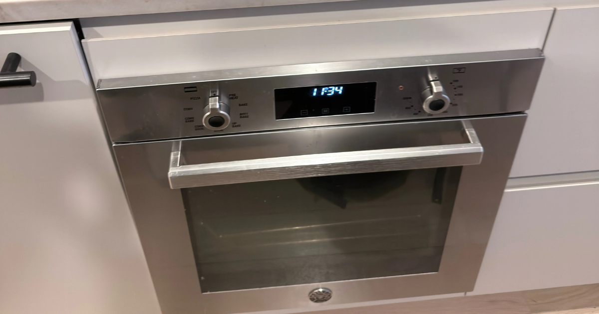 Three cats lying closely together on a white towel indoors, appearing relaxed and sleepy.