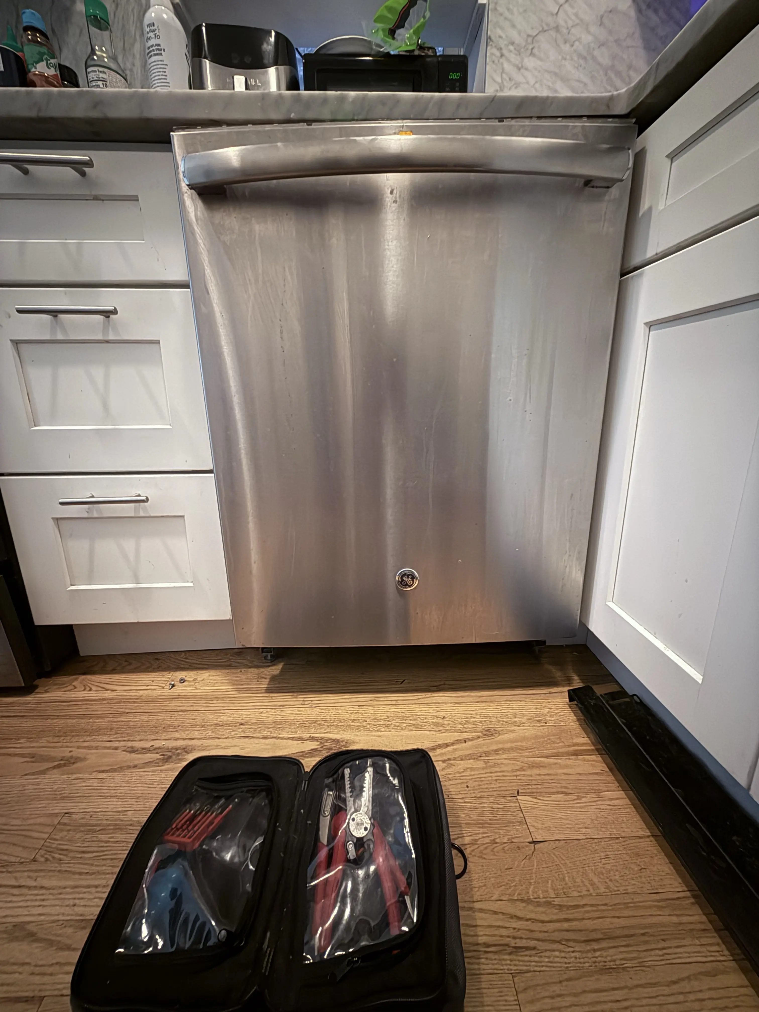 Stainless steel dishwasher with tool case on wooden kitchen floor