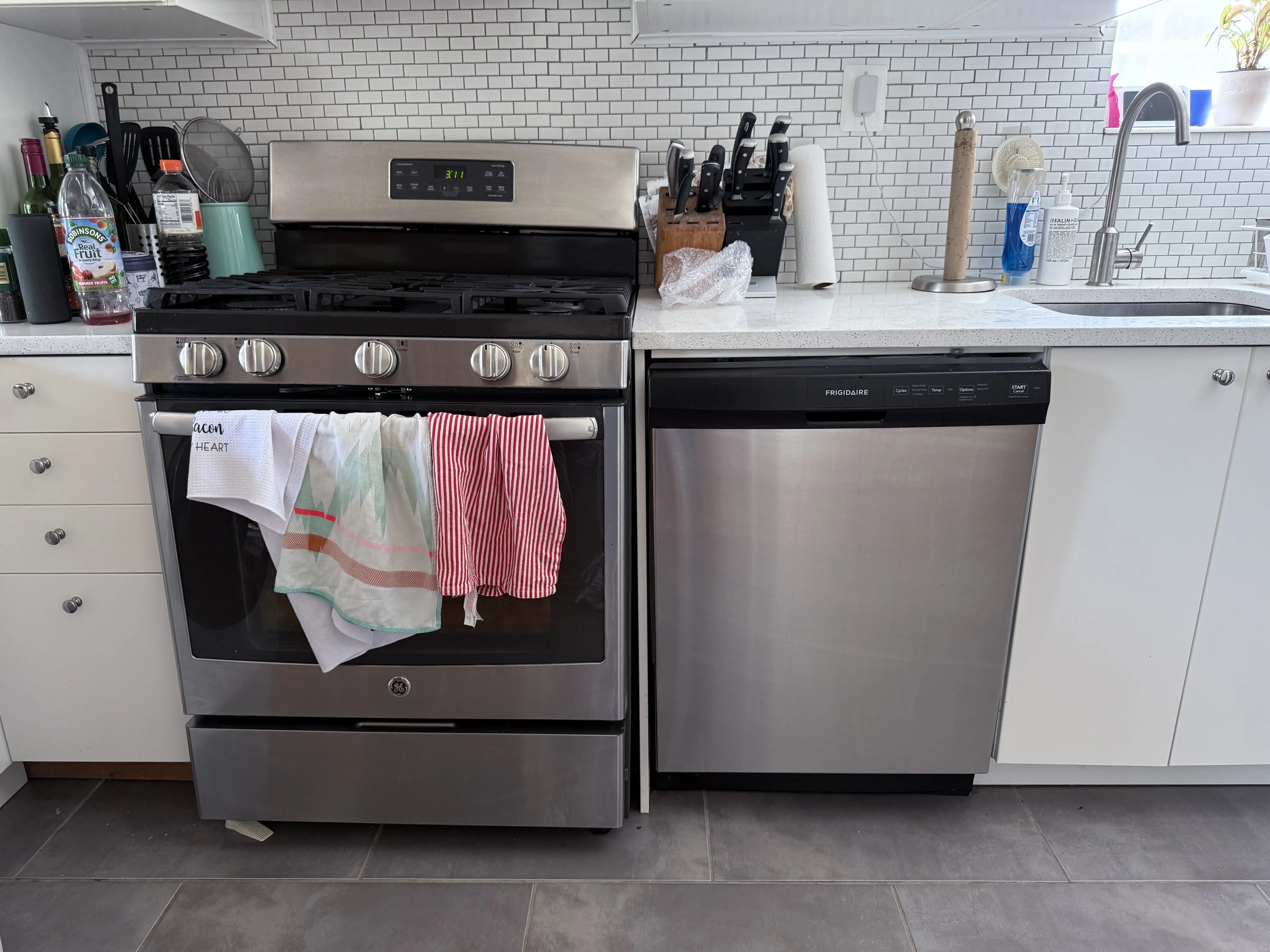 Stainless steel stove and dishwasher with kitchen towels in modern kitchen