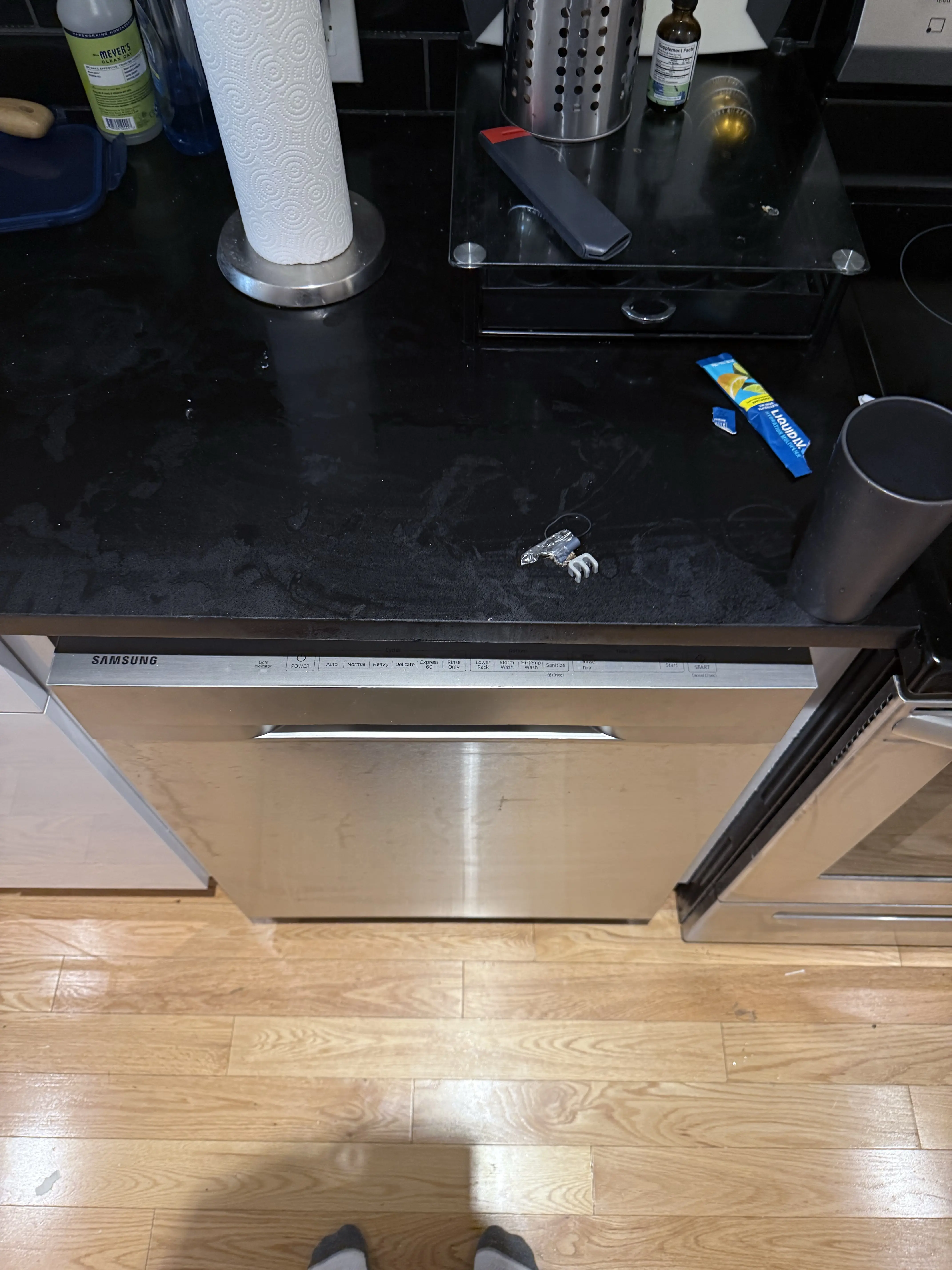 Samsung dishwasher with paper towel roll, cleaning supplies, and small objects