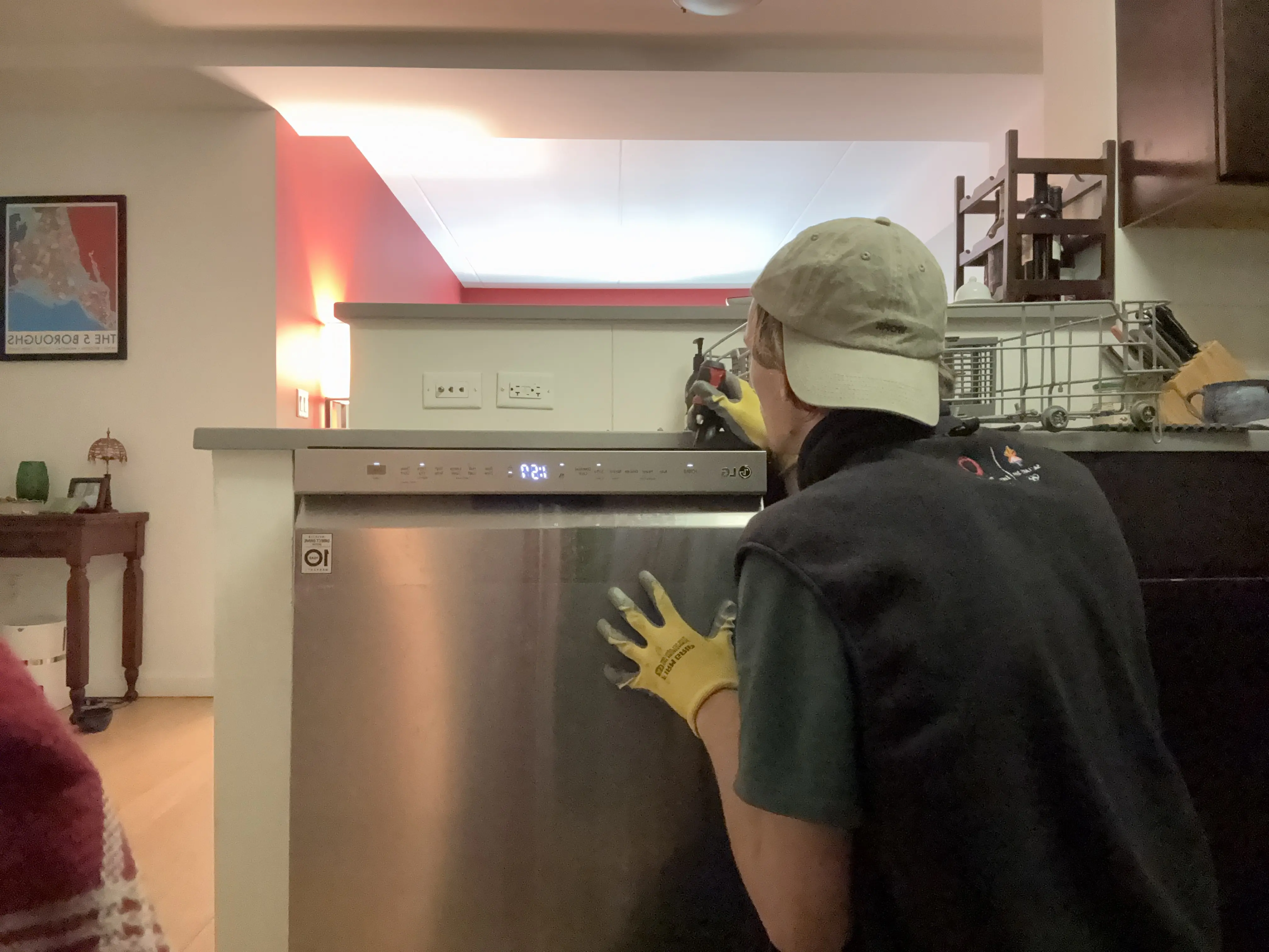 Technician in yellow gloves repairing a stainless steel dishwasher