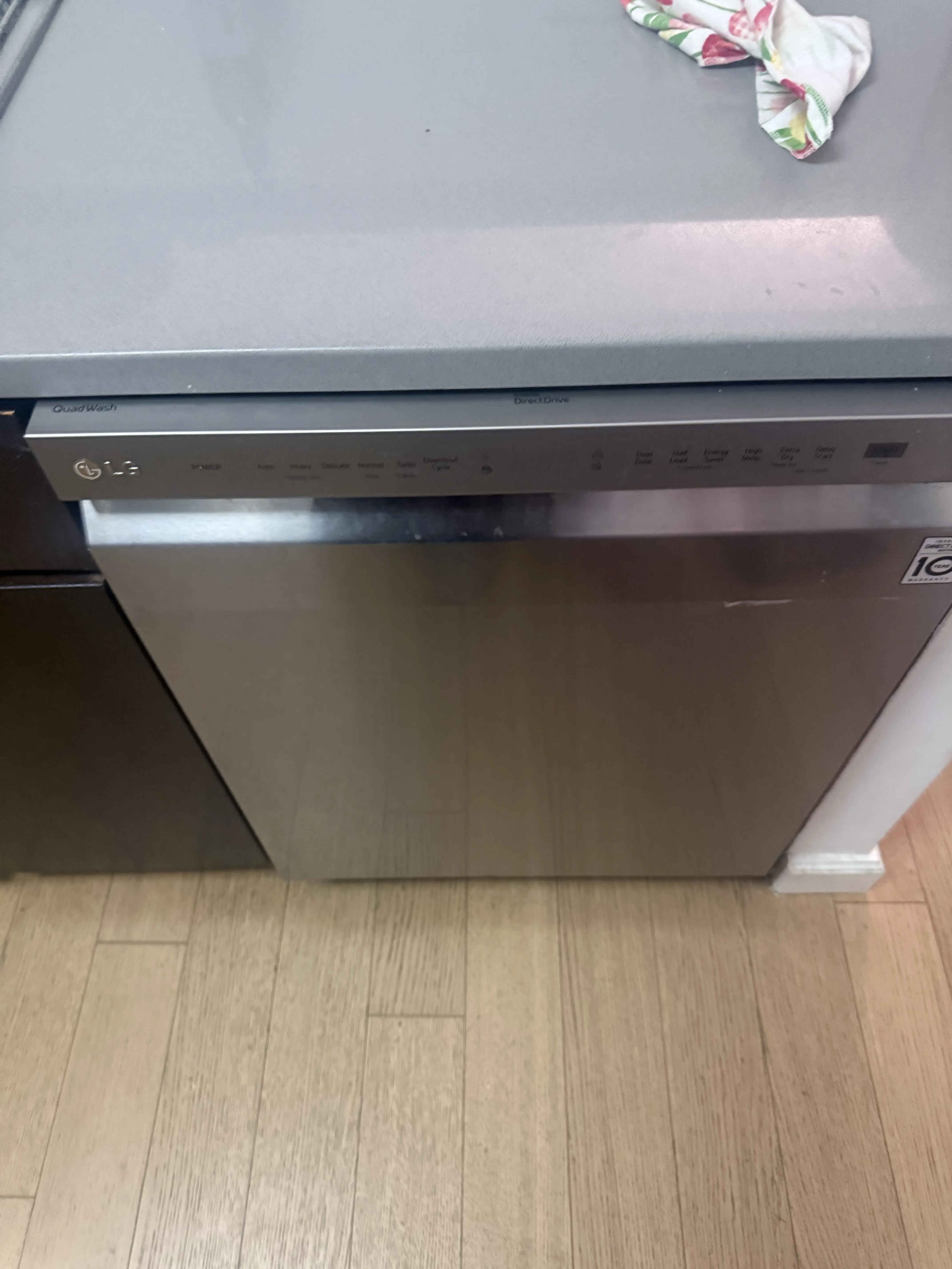 Stainless steel dishwasher with control panel, sitting on wooden floor