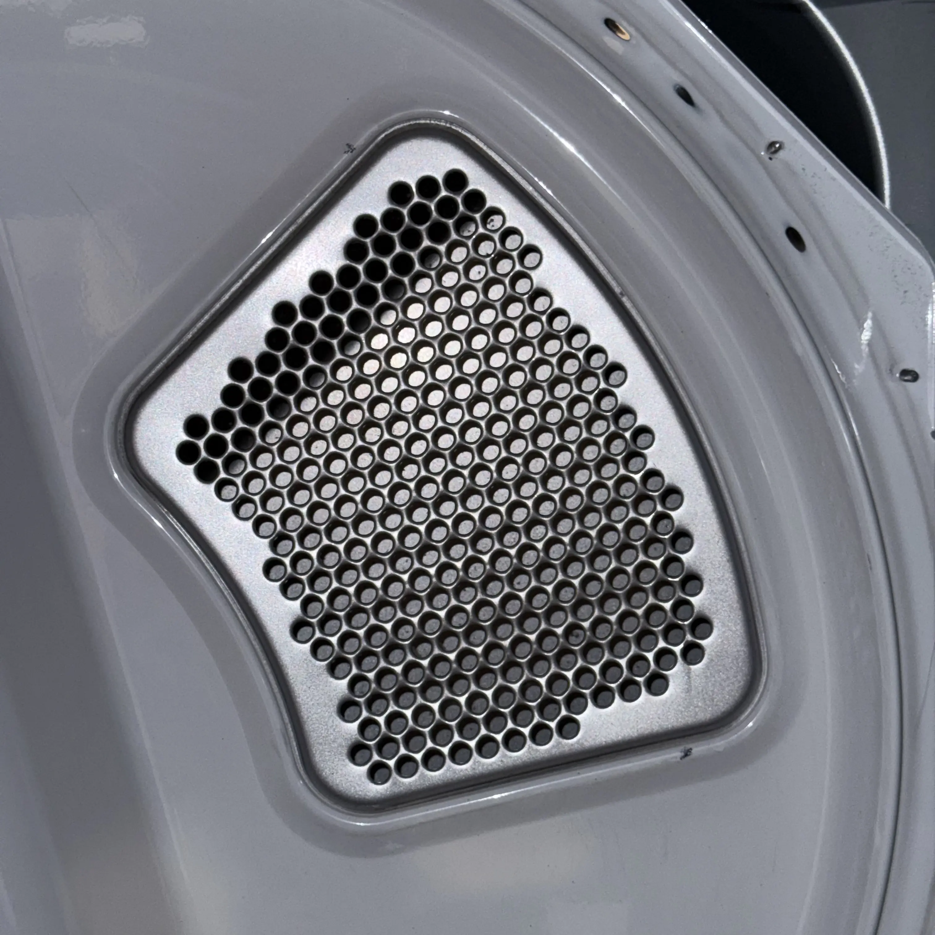 Dryer interior with perforated metal plate showing multiple small circular holes