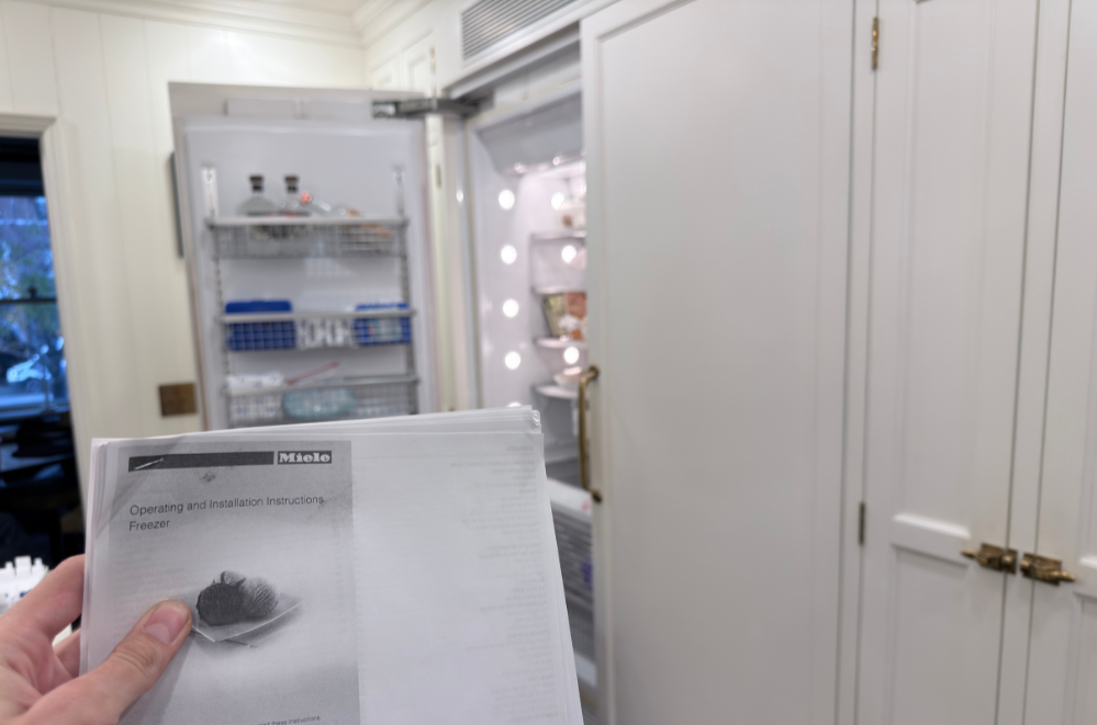 Blue gas stove with brass knobs and handles, a colorful towel hanging on the oven door, and a digital clock showing 5:32.