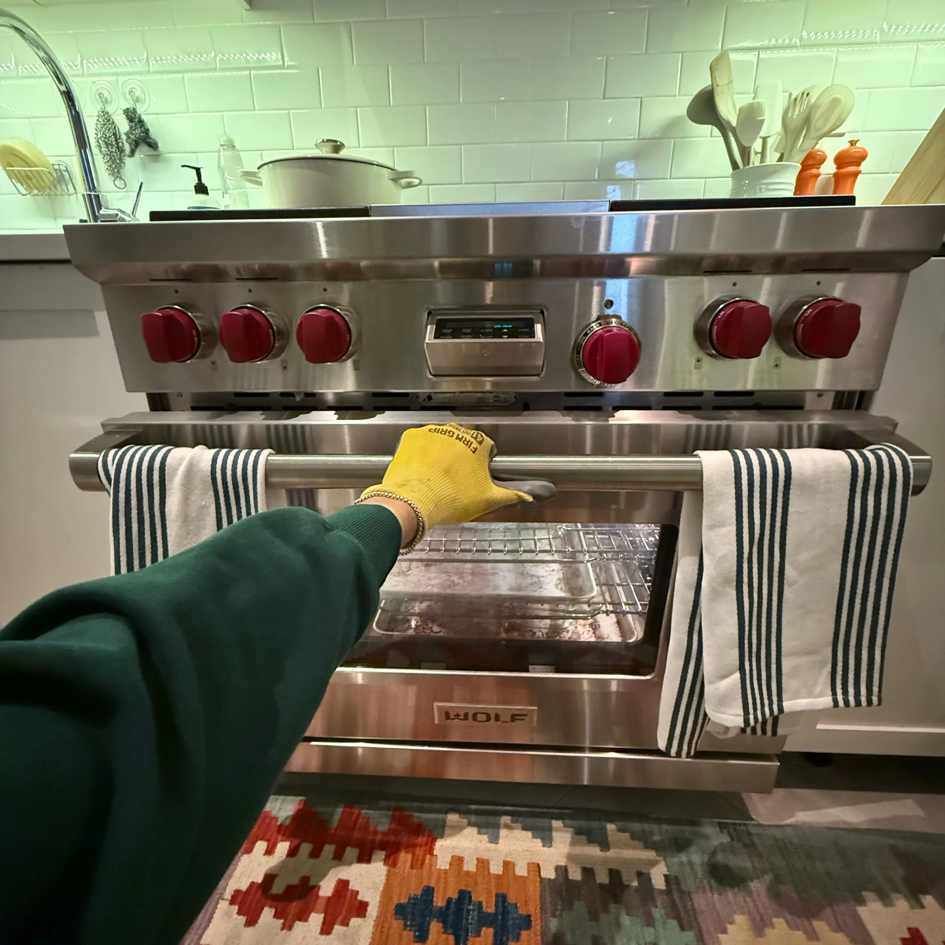 Modern kitchen corner featuring a stainless steel glass-door refrigerator, wooden cabinets, a mounted flat-screen TV, and a coffee machine on the countertop.