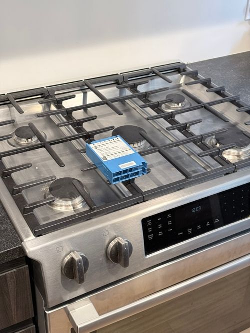 Open freezer filled with food items including ice cream tubs, boxed products, and vegetables, with a person kneeling in front of it.