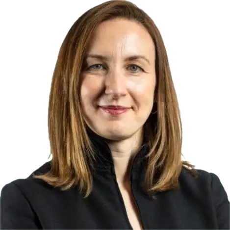 Woman with shoulder-length light brown hair wearing a black jacket, smiling confidently.