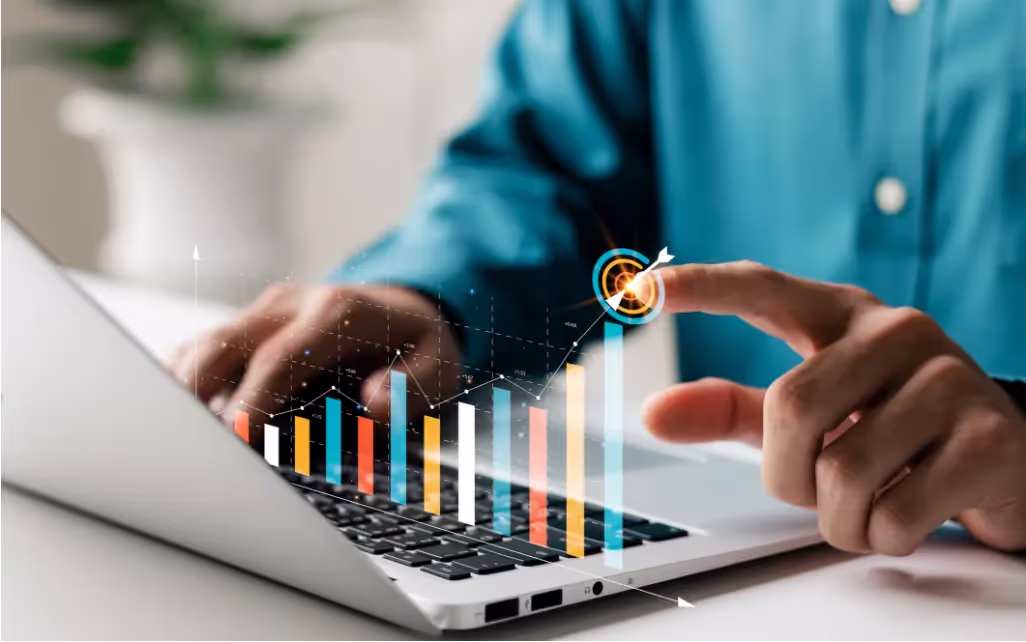 Les mains d'un homme devant son ordinateur portable, un doigt pointe vers une cible