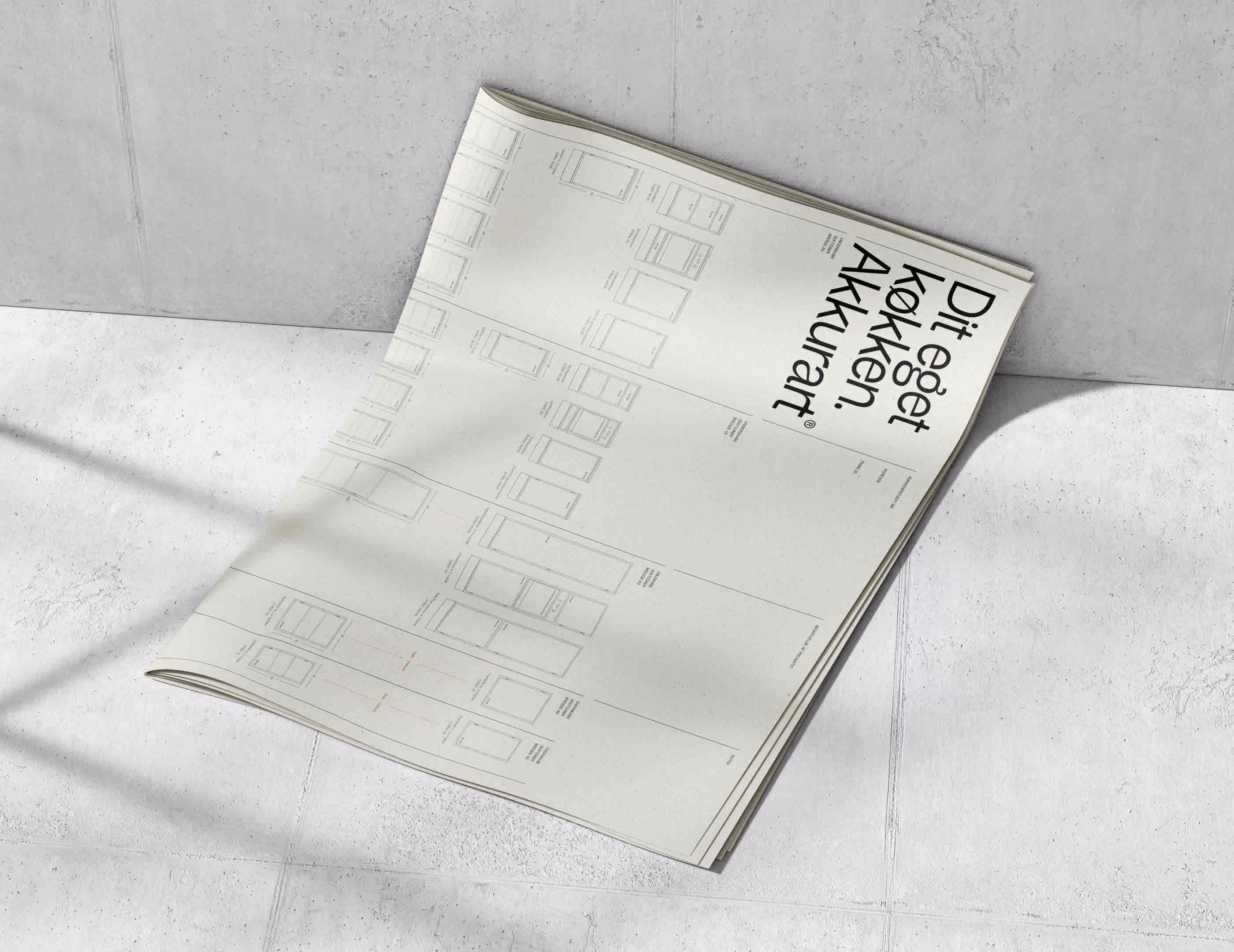 Åben designplan over køkkenskabe med teksten 'Dit eget køkken. Akkurat.' på en lys betonflisegulv.