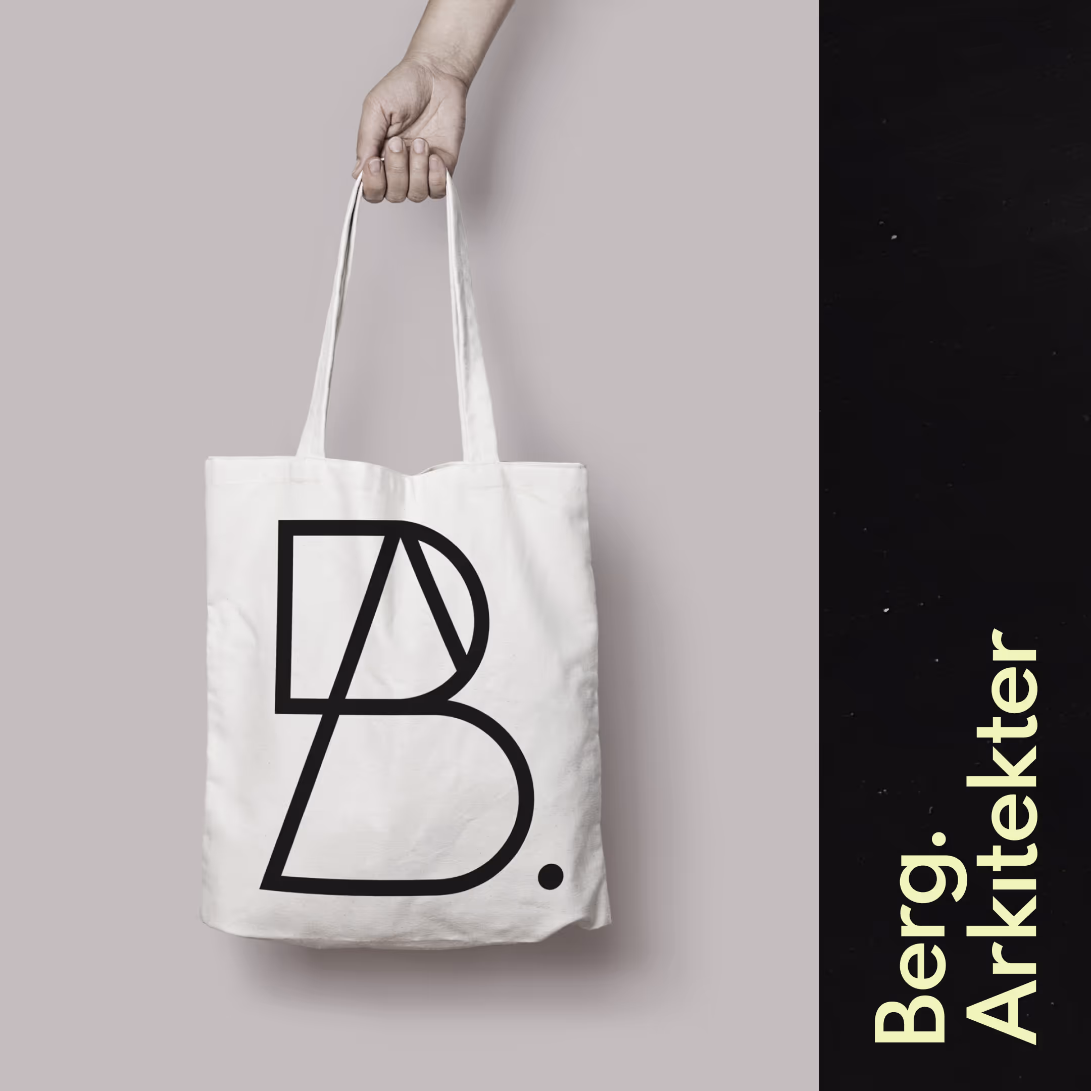 Hånd holder en hvid mulepose med et sort geometrisk logo og teksten 'Berg. Arkitekter' på en sort baggrund.