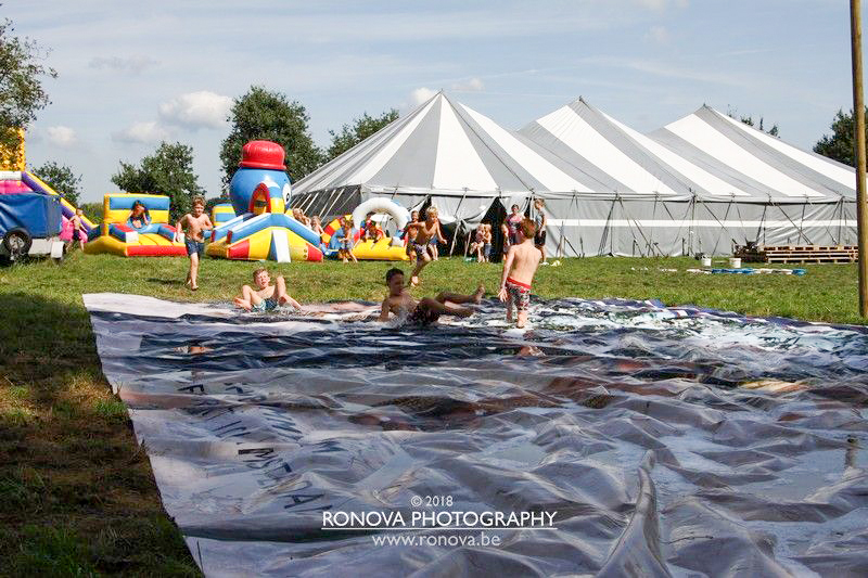 Overzichtfoto Doe Week terrein vol waterpret, springkussen en de grote feesttent in de achtergrond.