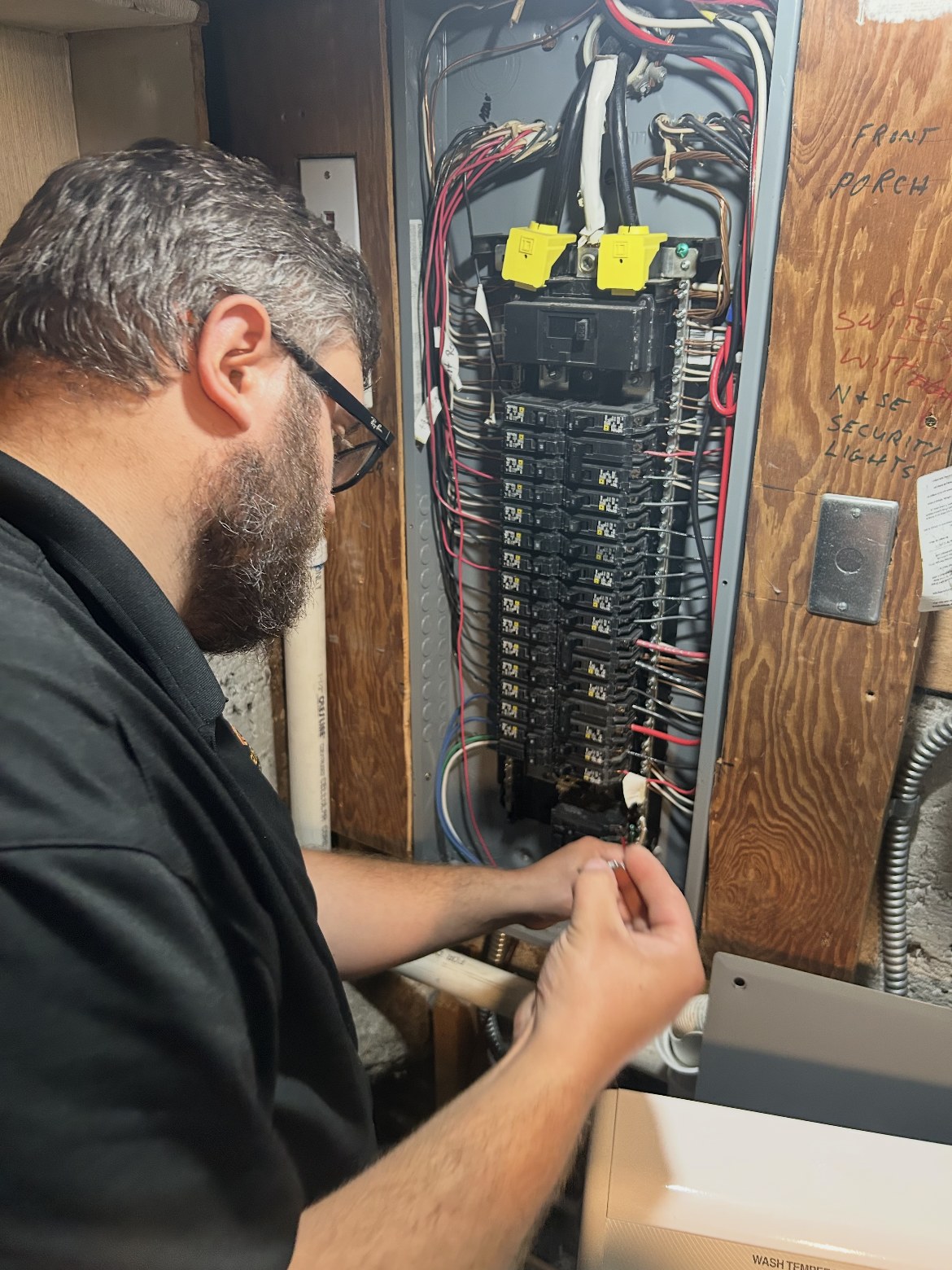 Good Guys electrician Richard working on a breaker inside an open electrical panel