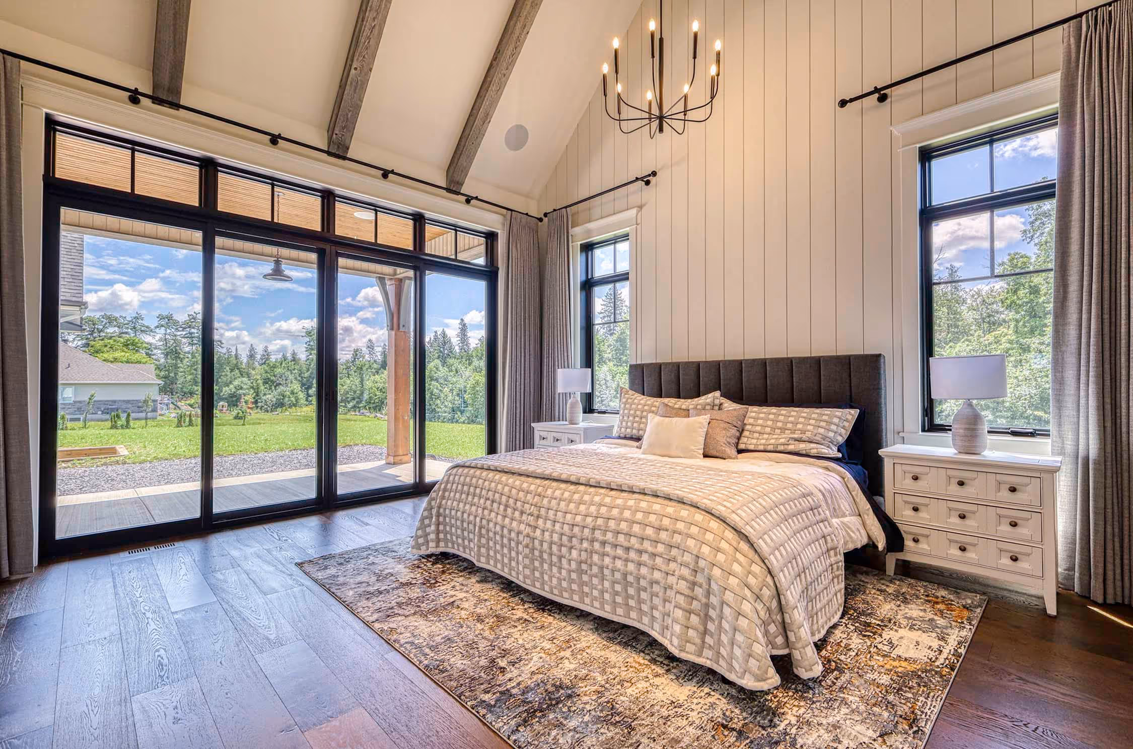 Large bedroom with a king bed in between two windows + a floor to ceiling window on the left wall.