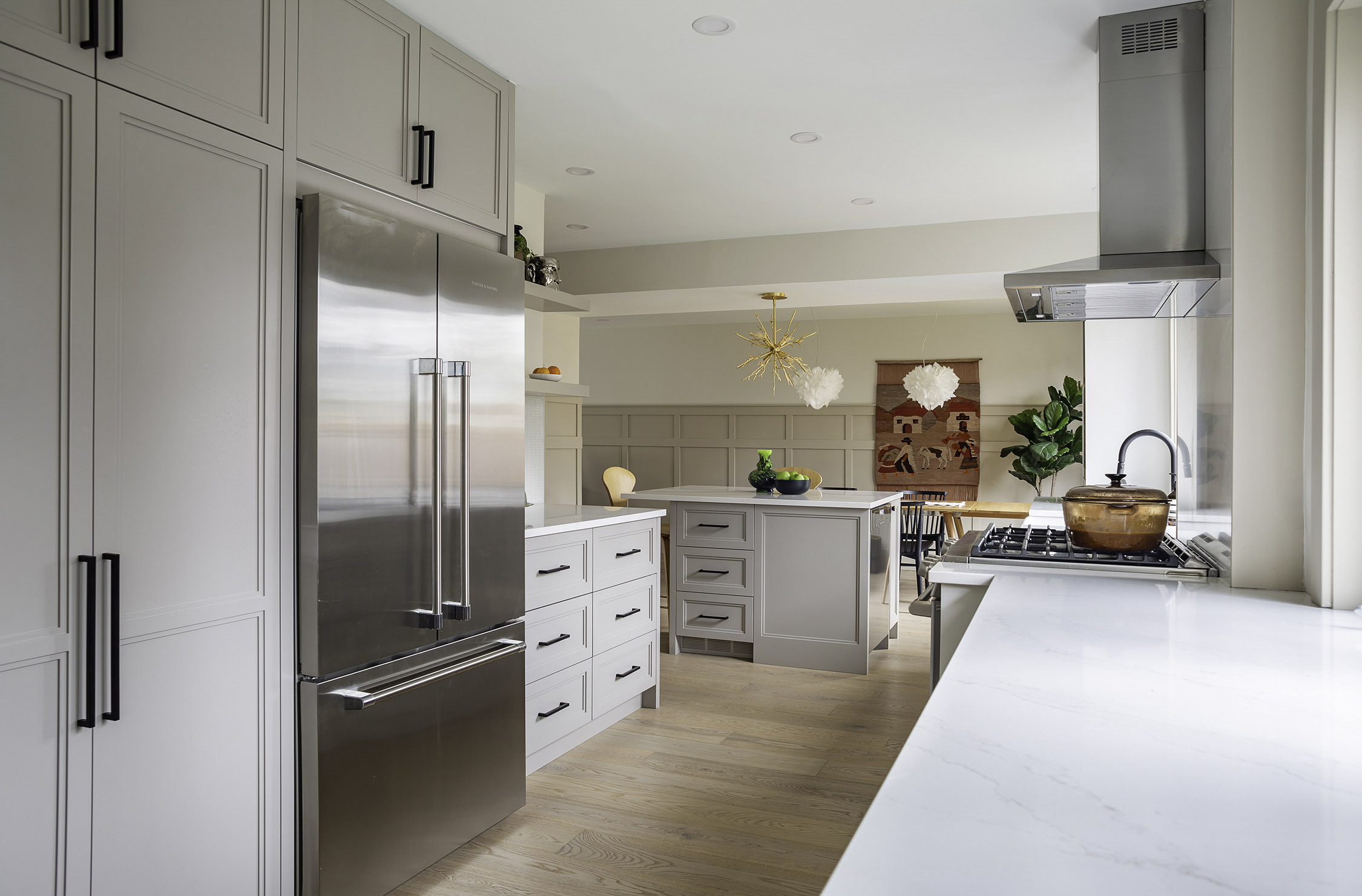 Large kitchen featuring white cabinets, light wood toned floors, and stainless-steel appliances. Architecture: Design Valley. Photography: Ursula Muntean. Copyright 2025.
