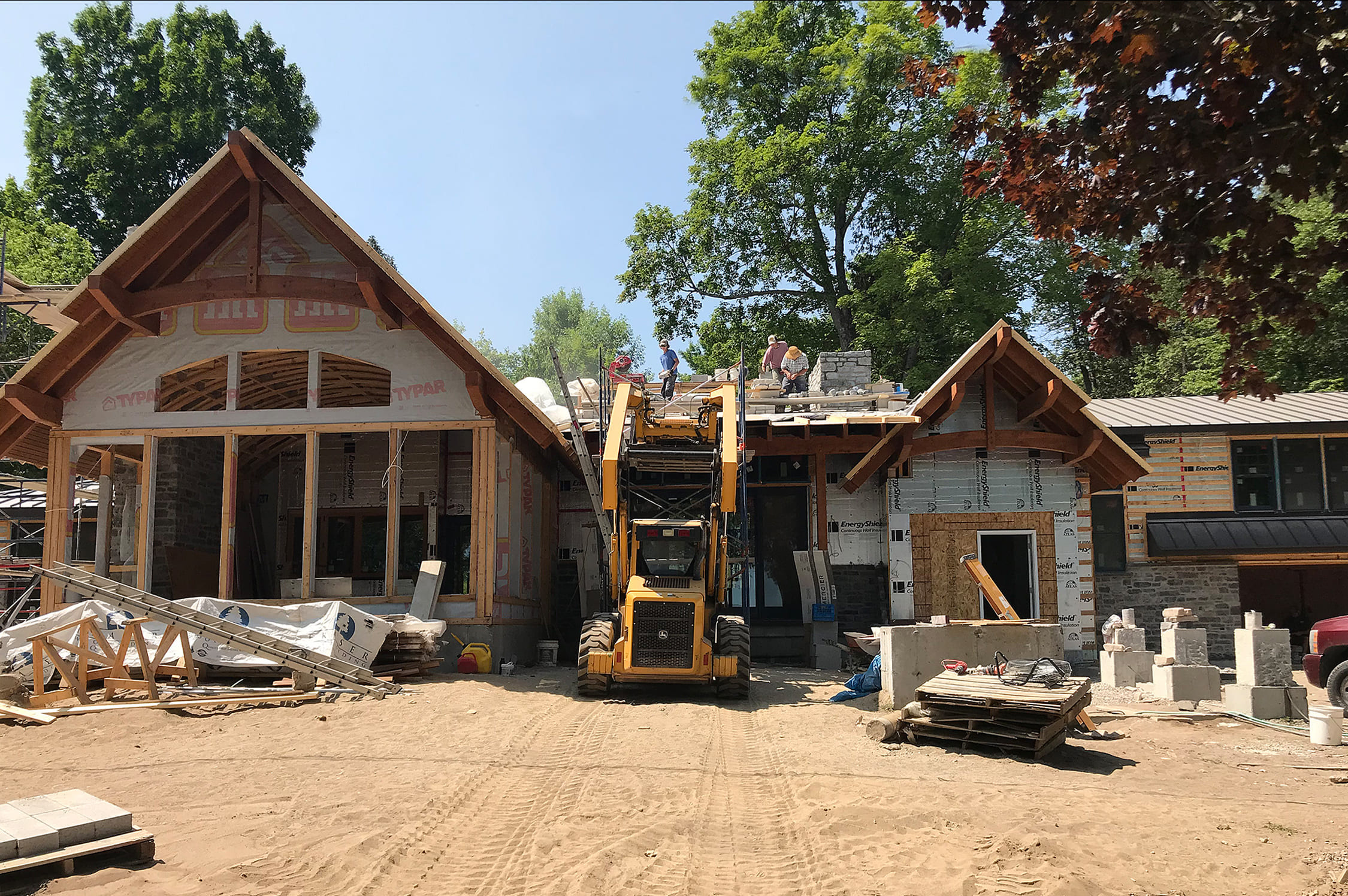House being built; building supplies and machinery on the job site.