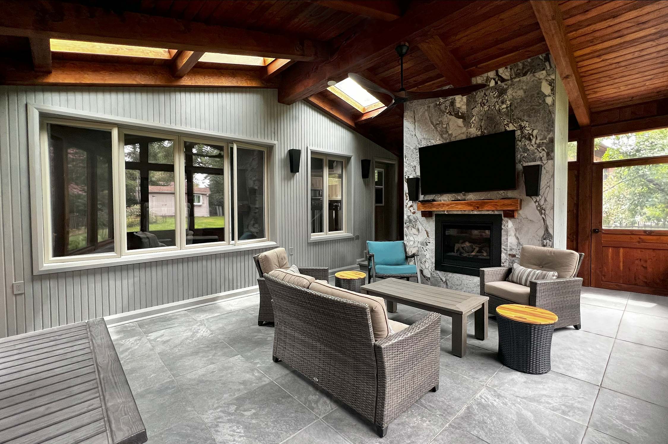 Three season family room with clean-lined timber, ceramic floor, seating, and a fireplace