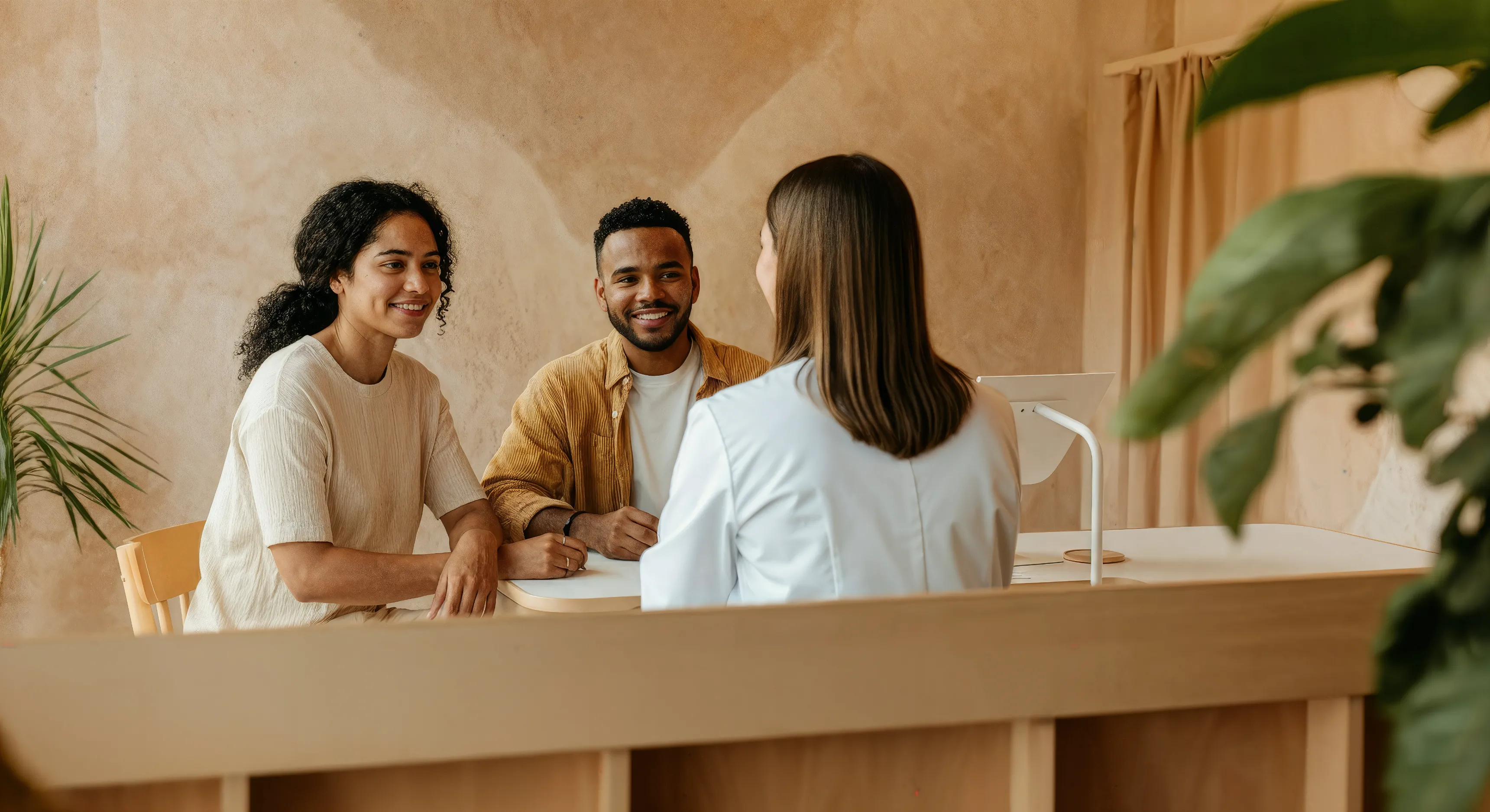 Un couple souriant qui parle avec une praticienne