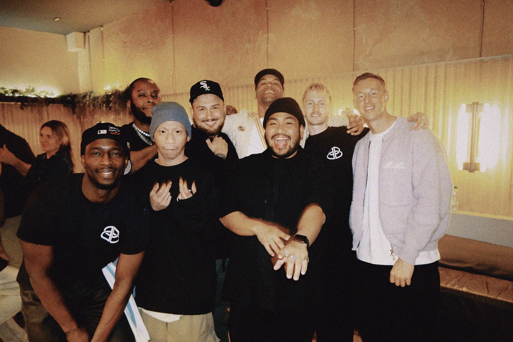 Group of smiling men posing together indoors in casual attire, some wearing caps and beanies. free range beef cattle essex burger restaurant staff