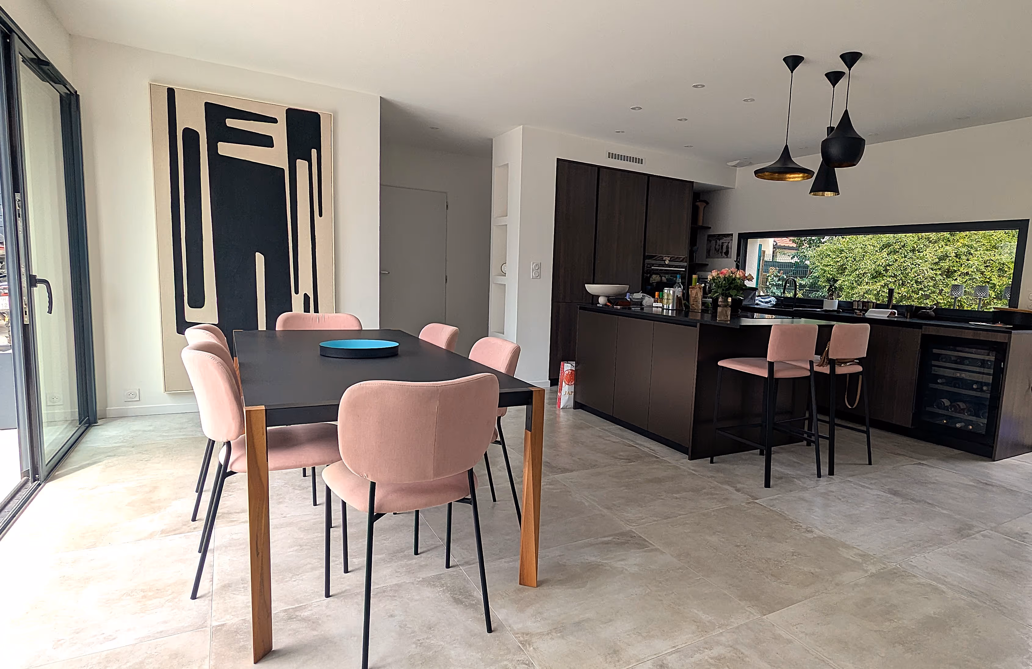 Un salon avec une table noir, des chaises roses