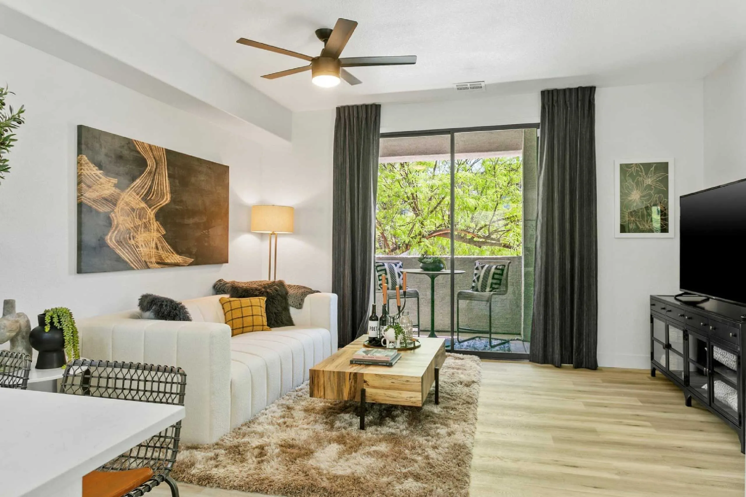 Modern living room with neutral tones, cozy decor, and a balcony view framed by large curtains.