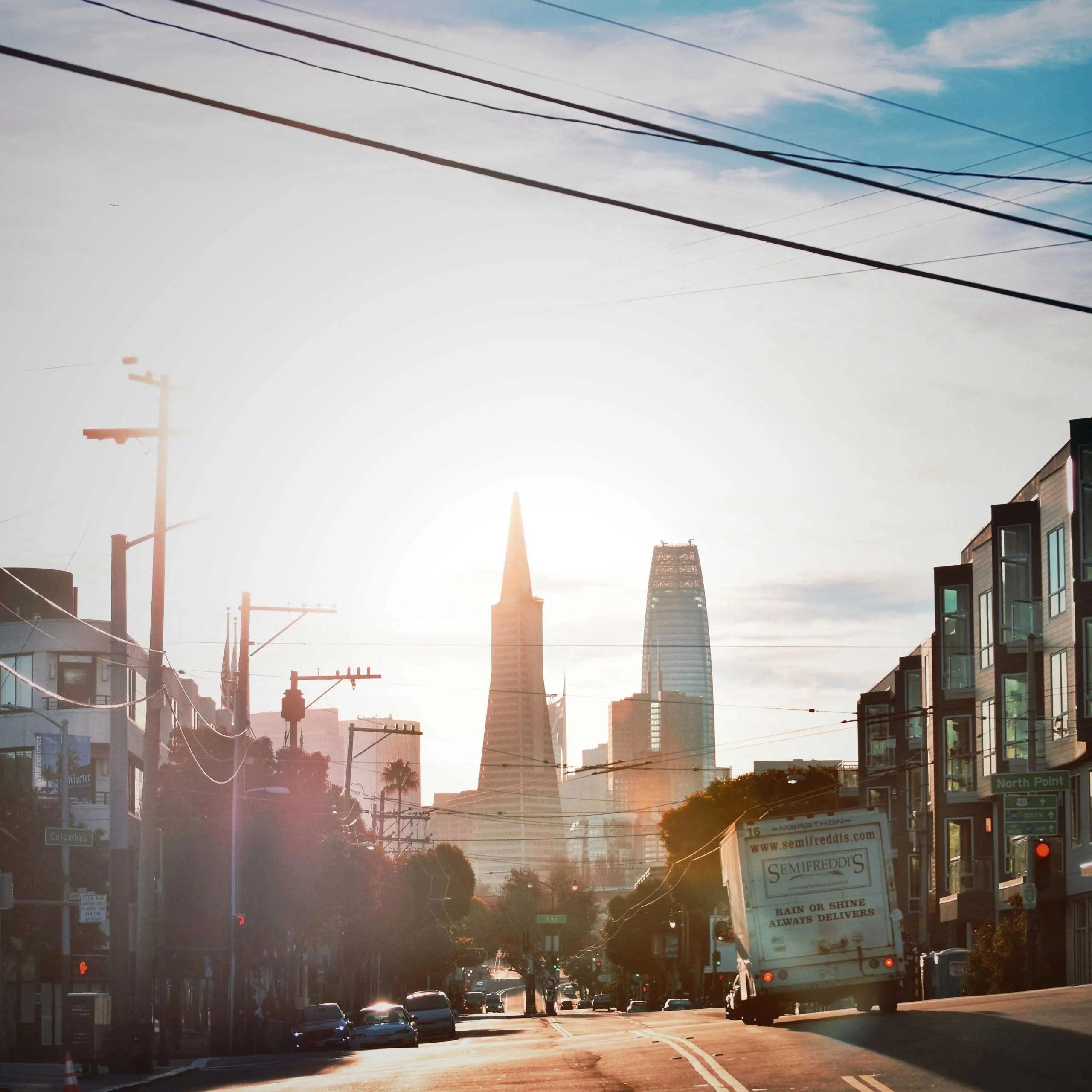 San Francisco street view with the Transamerica Pyramid and Salesforce Tower at sunrise.