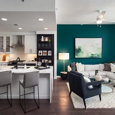 Modern open-concept living space with teal accent wall, sleek kitchen, and cozy seating area.