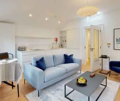 Modern open-plan living area with minimalist kitchen, sleek furniture, and soft lighting.