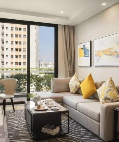 Modern living room with neutral tones, yellow accents, large window, and contemporary decor.