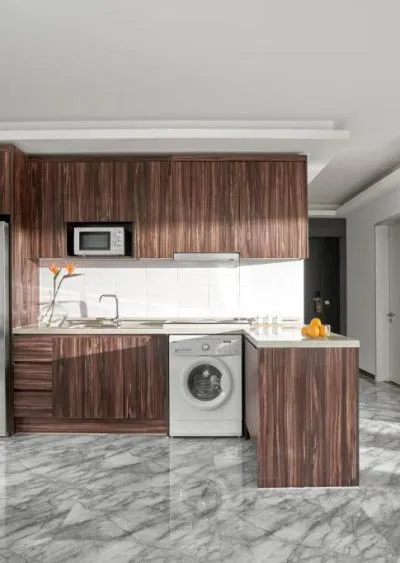 Modern kitchen with wood cabinetry, marble flooring, and integrated appliances.