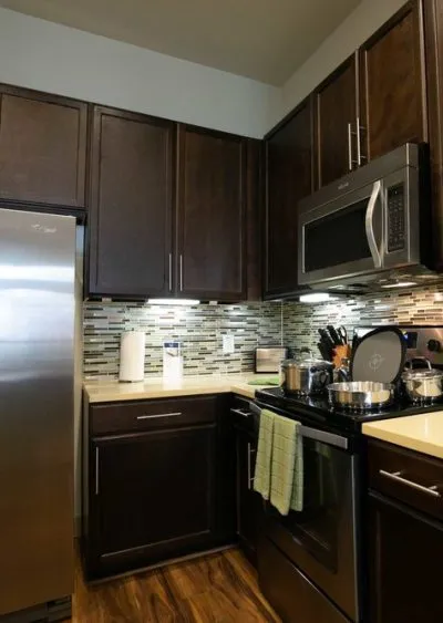 Modern kitchen with dark cabinets, stainless steel appliances, and mosaic tile backsplash.