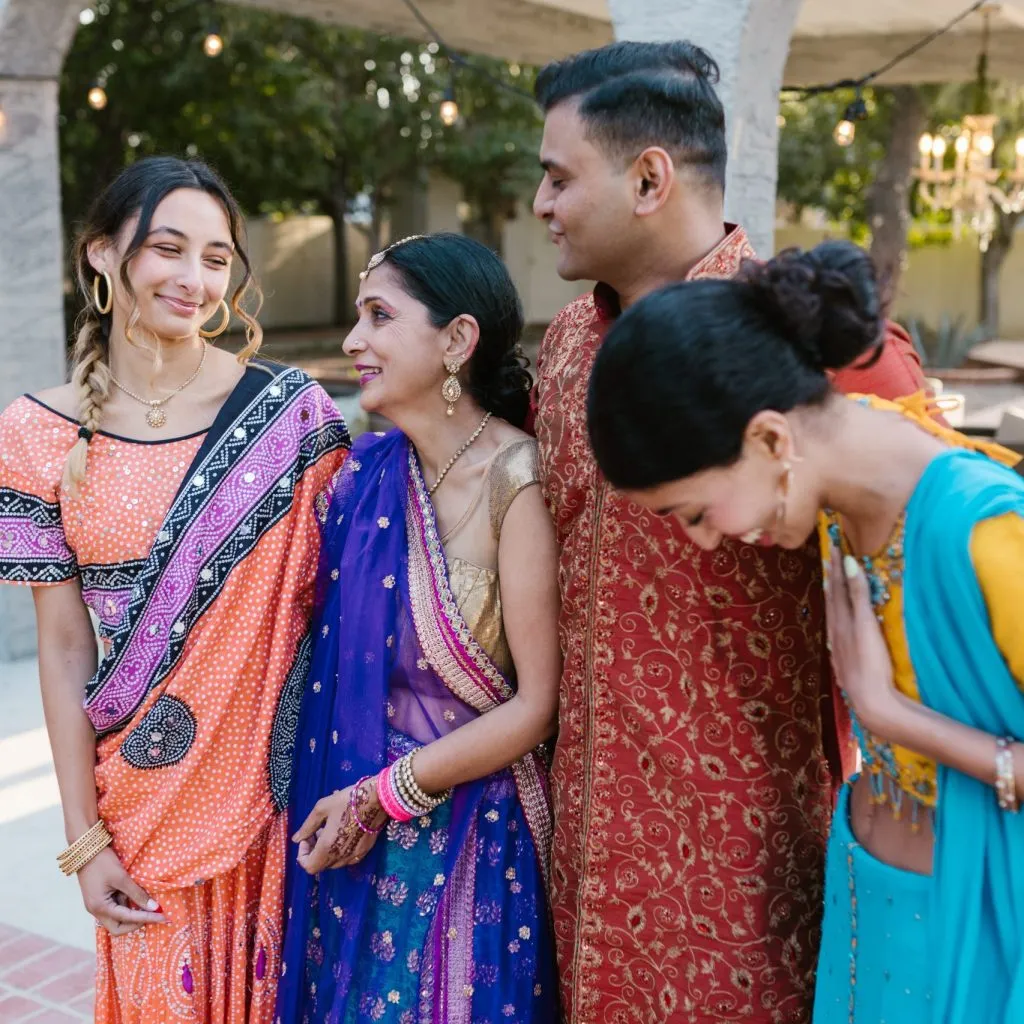 A group of people dressed in vibrant traditional Indian attire at an outdoor gathering.