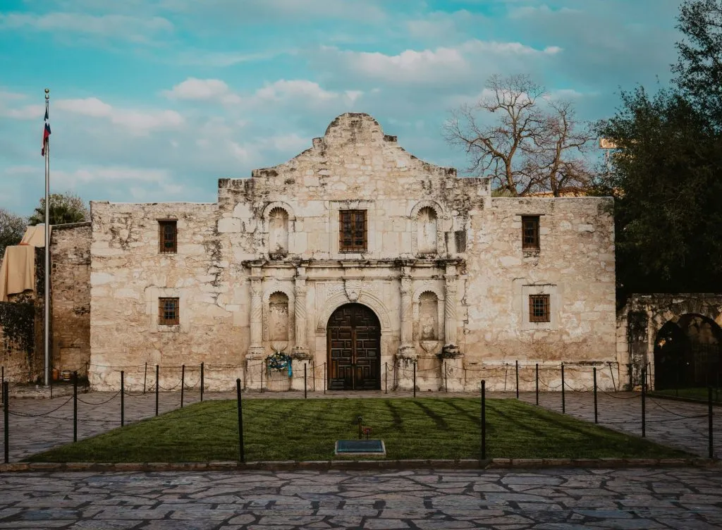 Historic facade of the Alamo mission in San Antonio, Texas, surrounded by a stone courtyard.
