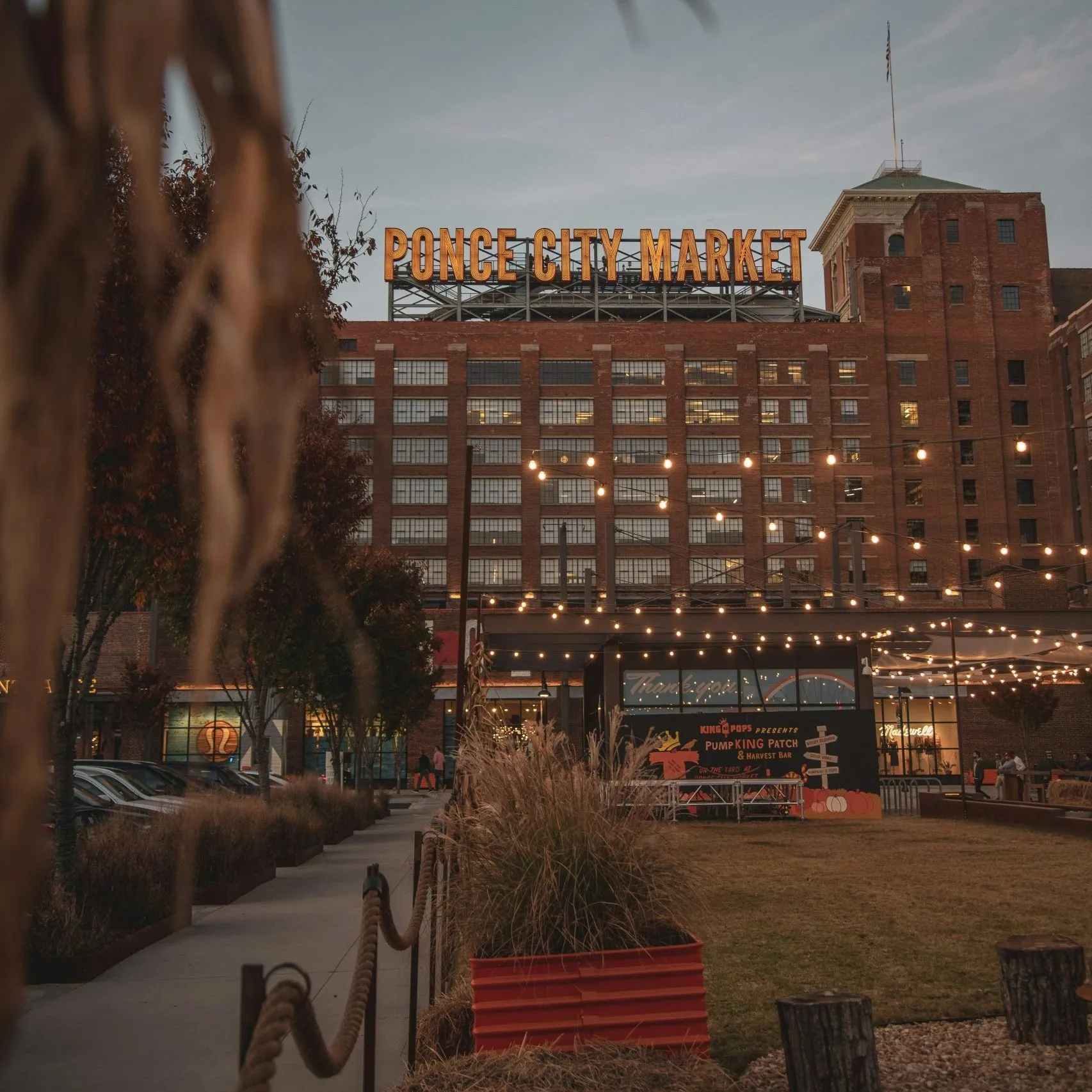 Ponce City Market's illuminated sign towers above a festive outdoor area with string lights.