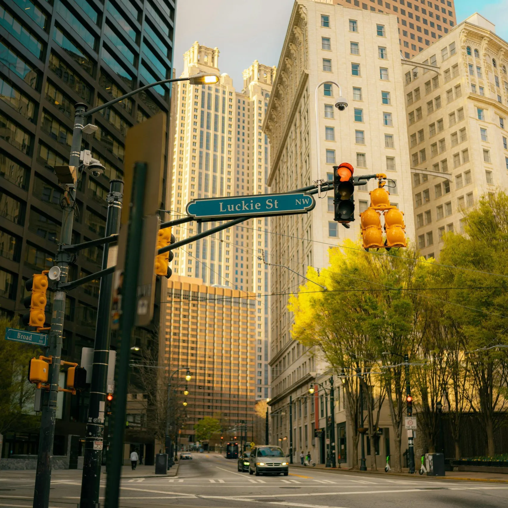 Urban street intersection with traffic lights, tall buildings, and a Luckie St NW sign.