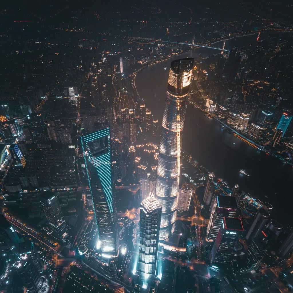Aerial view of Shanghai's illuminated skyline, featuring the Shanghai Tower and cityscape at night.