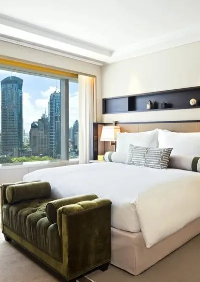 Elegant hotel room with city skyline view, modern decor, and plush green velvet seating.