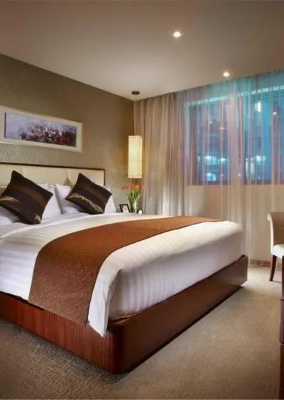 Elegant hotel room with a large bed, warm lighting, and modern decor featuring neutral tones.